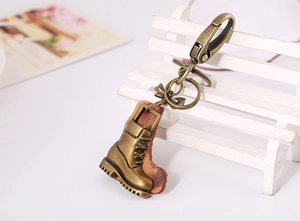 Macro detail of bronze boot pendant with leather backing and clasp on a wooden bench