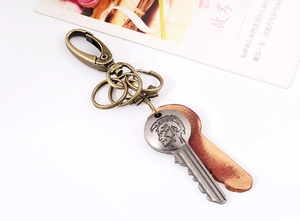 Macro detail of a vintage leather keychain with bronze portrait key and metal carabiner
