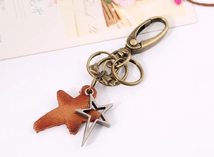 Detail of vintage bronze star pendant with brown leather texture and metal bow keychain