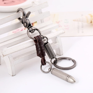 Retro brown leather keychain with vintage silver bullet pendant on a white miniature bench
