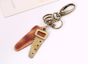 Close-up of a bronze saw charm and brown leather pendant on a vintage keychain