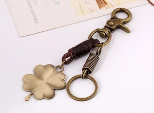Detail of vintage brass four-leaf clover keychain with dark brown braided leather strap