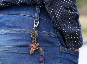 Retro bronze star keychain with brown leather hung on blue denim jeans belt loop
