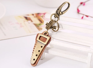Detail of vintage bronze saw pendant with brown leather backing on a key ring