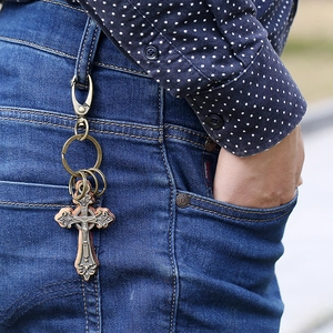 Porte-clés croix vintage en bronze avec insert en cuir suspendu à un jean denim