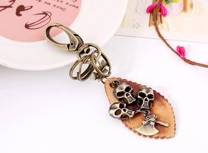 Detail of bronze skull and axe pendants on a vintage leather keychain accessory
