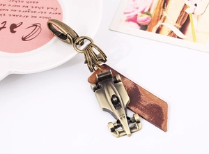 Macro detail of bronze metal F1 racing car keychain with genuine cowhide leather strap