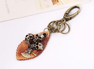 Close-up of vintage bronze punk keychain with skull charms and leather leaf pendant