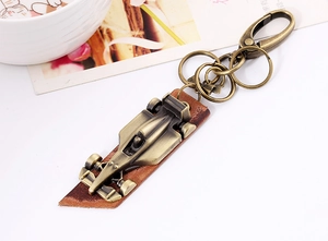 Macro view of vintage bronze F1 racing car keychain with brown leather base and lobster clasp