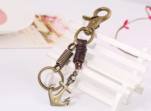 Detail of vintage bronze skull and anchor pendant on a brown leather keychain