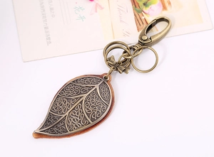 Close-up of bronze leaf keychain with hollow texture and premium leather backing