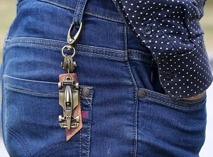 Retro bronze racing car leather keychain clipped to denim jeans belt loop as accessories
