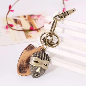 Retro bronze tribal mask keychain with brown leather accent on a white display stand