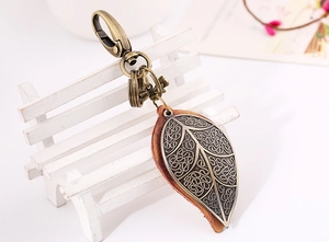 Detailed macro of vintage bronze leaf pendant on brown leather base with lobster clasp