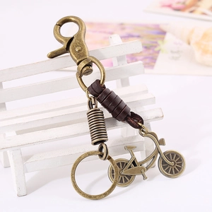 Vintage bronze bicycle keychain with brown leather wrap and lobster clasp on white bench