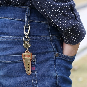 Vintage bronze saw pendant leather keychain hanging on a blue denim belt loop