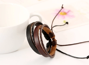 Dettaglio di bracciali in pelle multistrato con corde intrecciate e chiusura a coulisse