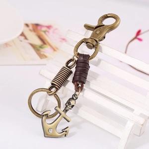 Vintage bronze skull anchor keychain with brown leather wrap on a white bench