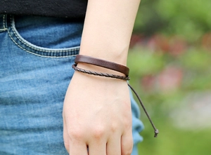 Dettaglio del bracciale in pelle marrone a più strati con chiusura regolabile al polso