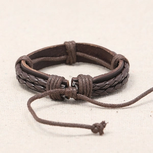 Handmade braided brown leather bracelet with adjustable cord on textured linen background