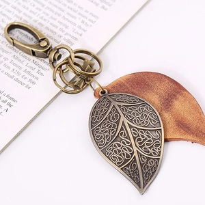 Retro bronze leaf pendant keychain with leather layers and three split rings on a book