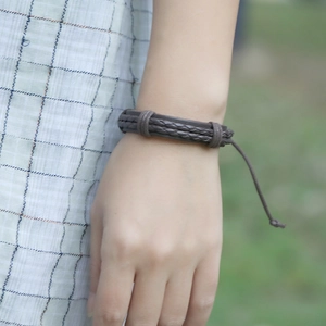 Detail of hand-woven dark brown leather bracelet with adjustable drawstring closure