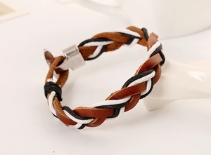 Detailed view of brown braided leather bracelet with silver clasp on hand display
