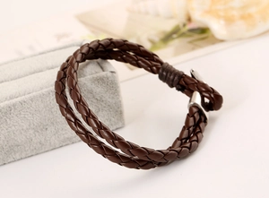 Detailed macro of dark brown braided PU leather bracelet with silver metal buckle