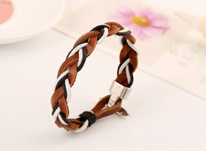 Detail of woven leather bracelet with silver metal magnetic clasp on a soft background