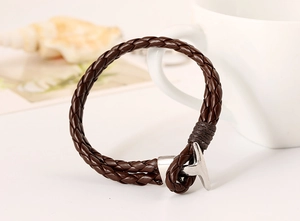 Close-up of brown braided leather bracelet featuring a silver metal T-bar clasp closure