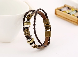 Macro detail of braided leather bracelet featuring vintage bronze rose charms and clasp