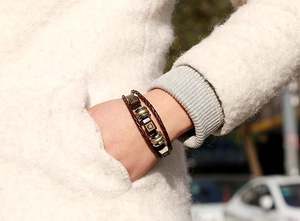Dettaglio del bracciale multistrato in pelle intrecciata vintage con borchie in bronzo