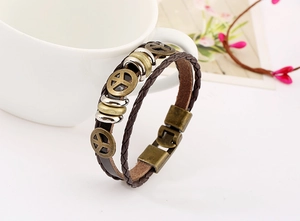 Detail of woven brown leather bracelet featuring vintage bronze peace sign charms