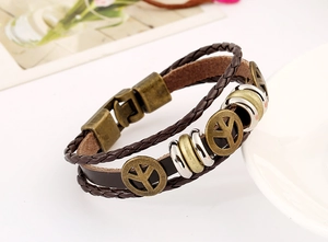 Detail view of multi-layer brown leather bracelet with bronze peace sign charms and rings