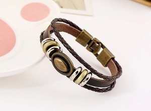 Macro view of vintage multilayer braided leather bracelet with embossed bronze medallion