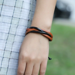 Détail du bracelet en cuir tressé noir et marron avec cordon réglable sur le poignet