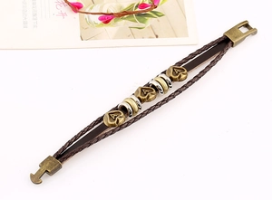 Macro detail of braided leather bracelet with bronze heart charms and metal spacers