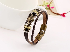 Detail of vintage braided leather bracelet with bronze rings on a ceramic cup edge