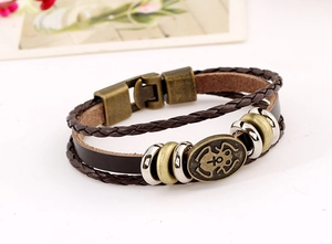 Detail of multi-layer vintage braided leather bracelet with antique metal beads and charms