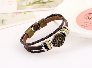 Macro detail of braided brown leather bracelet with vintage 1990 coin charm and bronze clasp