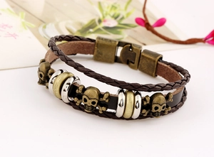 Detail of punk leather bracelet showing bronze skull charms and multi-layer braided straps