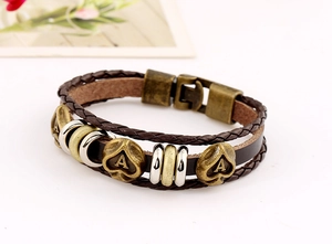 Detail of vintage braided leather bracelet with multilayered straps and spade metal charms