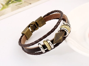 Detail of vintage layered leather bracelet featuring braided cords and bronze metal clasp