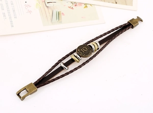 Close-up of a vintage multilayer leather bracelet with a bronze coin and metal clasp