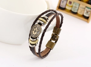 Detail of vintage braided leather bracelet with bronze oval charm and metallic spacers