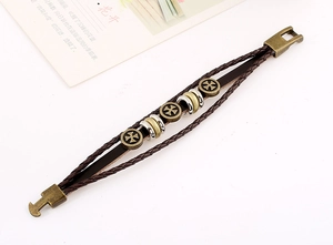 Detail of vintage multilayer braided leather bracelet with cross charms and T-bar clasp