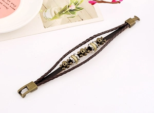 Detail view of multi-layer braided leather bracelet with bronze skull and metal buckles
