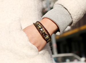 Macro detail of multi-layer braided leather bracelet with vintage bronze skull charms