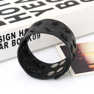 Détail d'un bracelet large en cuir noir montrant la texture tressée et quatre pressions argentées