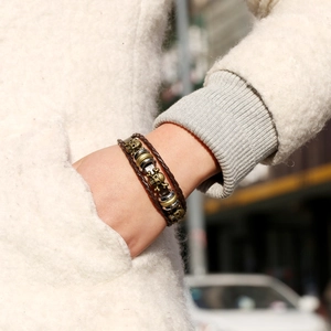 Punk leather bracelet with bronze skulls and braided cords on a model's wrist